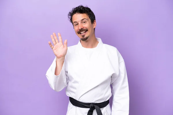 Young Caucasian Man Doing Karate Isolated Purple Background Saluting Hand — Stock fotografie