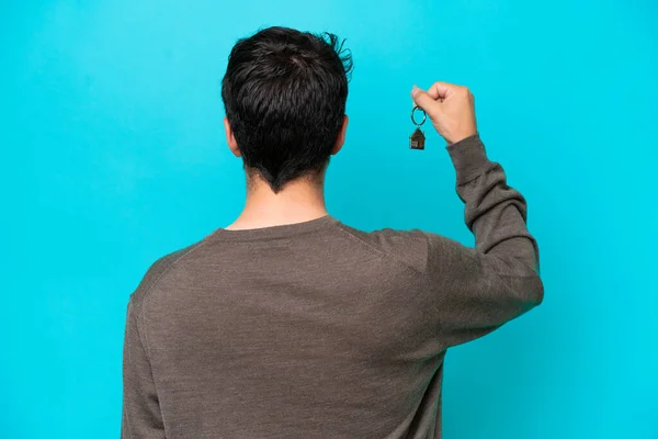 Young Caucasian Man Holding Home Keys Isolated Blue Background Back — 스톡 사진