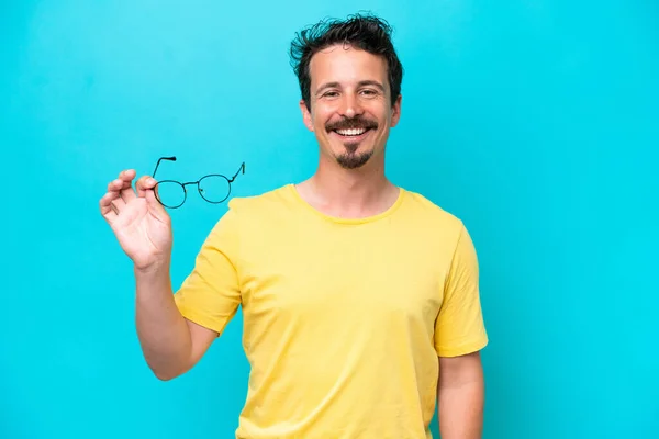Young Caucasian Man Holding Glasses Isolated Blue Background Smiling Lot — Foto de Stock