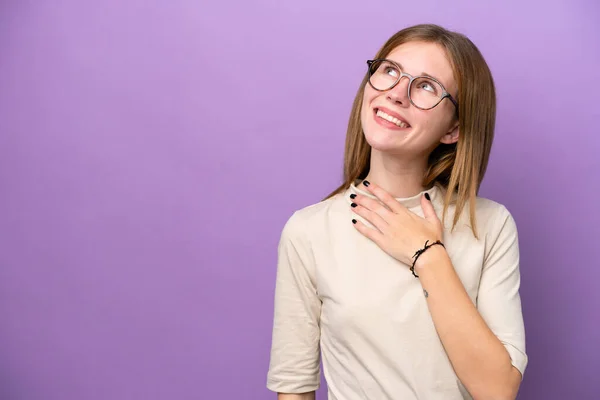 Young English woman isolated on purple background looking up while smiling