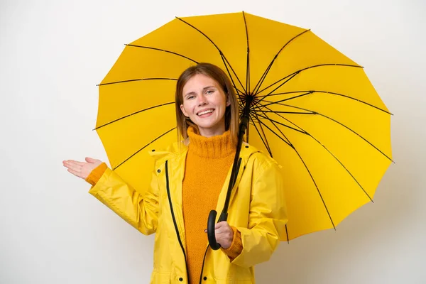 若いです英国人女性でレインプルーフコートと傘は白い背景に手を伸ばします側に来るために招待のために — ストック写真