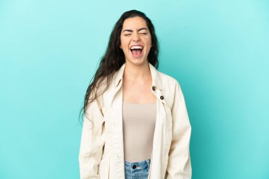 Kafkasyalı genç bir kadın mavi arka planda izole edilmiş ve ağzı açık bağırıyor.