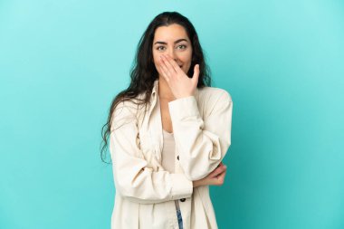 Mavi arka planda izole edilmiş genç beyaz kadın sağa bakarken şaşırdı ve şok oldu.