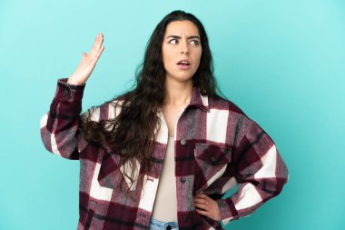 Kafkasyalı genç bir kadın mavi arka planda izole edilmiş, yorgun ve hasta bir ifadeyle.