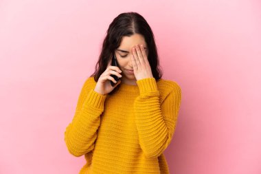 Young caucasian woman using mobile phone isolated on pink background with tired and sick expression
