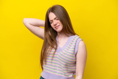 Sarı arka planda boynu ağrıyan genç beyaz kadın.