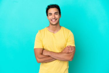 Izole mavi arka plan üzerinde Kafkas yakışıklı adam kollarını ön konumda geçti tutarak