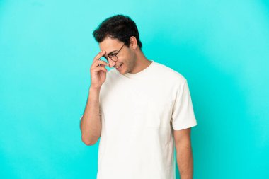 Kafkasyalı yakışıklı adam soyutlanmış mavi arka planda gülüyor.