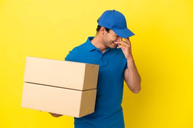 Delivery man over isolated yellow wall laughing