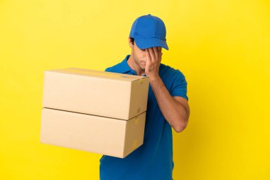 Delivery man over isolated yellow wall with tired and sick expression