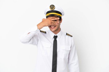 Airplane pilot over isolated white background covering eyes by hands and smiling