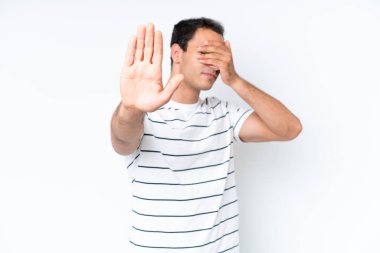 Beyaz arka planda izole edilmiş genç beyaz adam jesti durduruyor ve yüzünü kapatıyor.