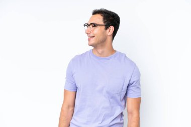 Beyaz arka planda izole edilmiş genç beyaz adam yana bakıyor ve gülümsüyor.