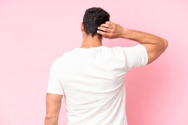 Kafkasyalı genç adam pembe arka planda izole edilmiş ve düşünüyor.