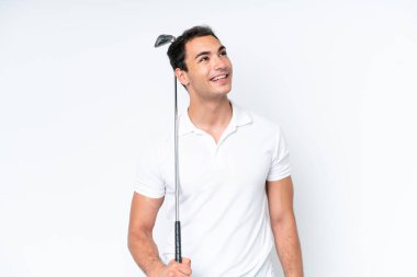 Young caucasian man isolated on white background playing golf and looking up while smiling