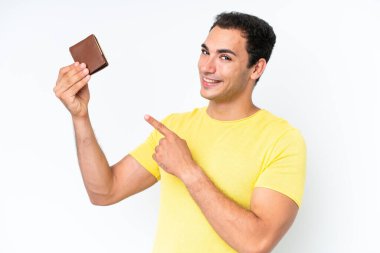Young caucasian man holding a wallet isolated on white background and pointing it