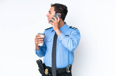 Beyaz arka planda izole edilmiş genç bir beyaz adam elinde kahve ve bir cep telefonu tutuyor.