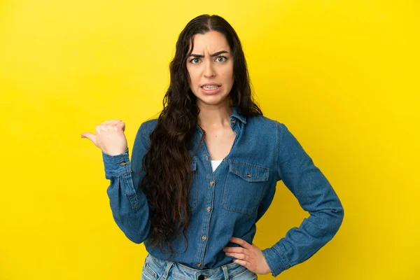 Giovane Donna Caucasica Isolato Sfondo Giallo Infelice Indicando Lato — Foto Stock