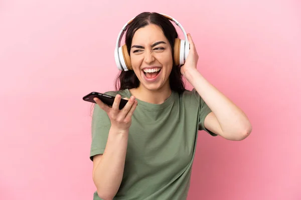 Joven Mujer Caucásica Aislada Sobre Fondo Rosa Escuchando Música Con —  Fotos de Stock