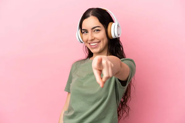 Giovane Donna Caucasica Isolata Sfondo Rosa Ascoltando Musica Indicando Parte — Foto Stock
