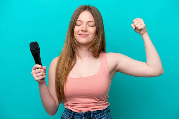 Singer Caucasian Woman Picking Microphone Isolated Blue Background Doing Strong — Stok fotoğraf