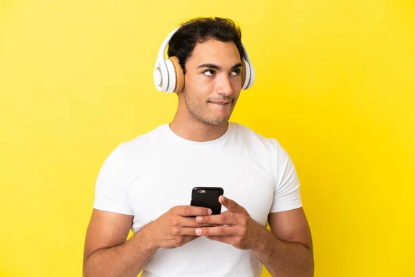 Белый Красивый Мужчина Изолированном Желтом Фоне Слушает Музыку Мобильным Телефоном — стоковое фото