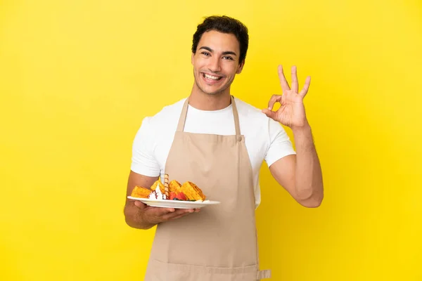 Restaurant Waiter Holding Waffles Isolated Yellow Background Showing Sign Fingers — Photo