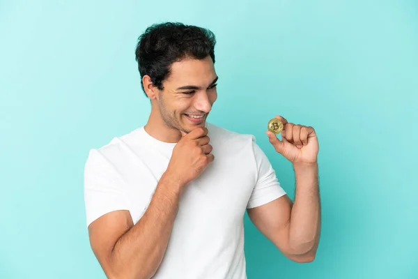 Young Man Holding Bitcoin Isolated Blue Background Looking Side Smiling — Stock Photo, Image