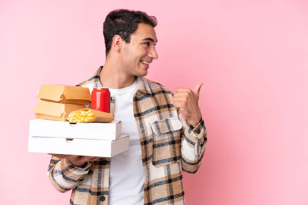 Young Caucasian Man Holding Fast Food Isolated Pink Background Pointing — Photo