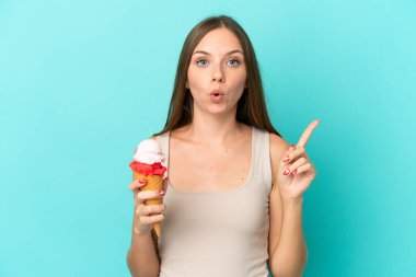 Kornet dondurmalı genç Litvanyalı kadın, mavi arka planda tek parmağını kaldırarak çözümü bulmaya çalışıyor.