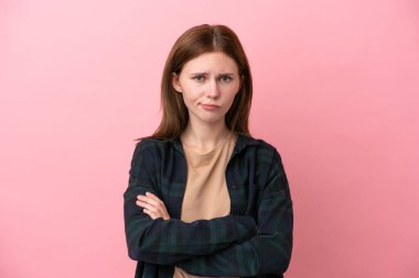 Genç İngiliz kadın pembe arka planda mutsuz bir ifadeyle izole edilmiş.