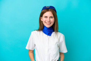 Uçak hostesi İngiliz kadın mavi arka planda izole edilmiş gülüyor.