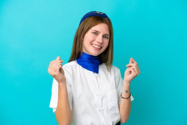 Uçak hostesi İngiliz kadın mavi arka planda izole edilmiş para hareketi yapıyor.