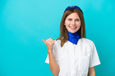 Mavi arka planda izole edilmiş İngiliz hostes bir ürünü sunmak için kenarı işaret ediyor.