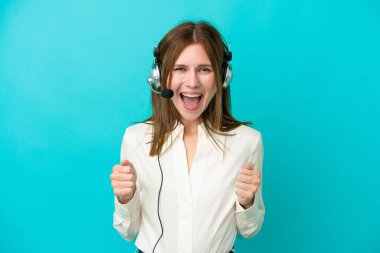 Mavi arka planda izole edilmiş kulaklıkla çalışan pazarlamacı İngiliz kadın galibiyeti kutluyor.