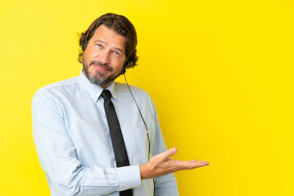 黄色の背景に隔離されたヘッドセットで働いているテレマーケティング担当者が笑顔を見せながらアイデアを提示 — ストック写真