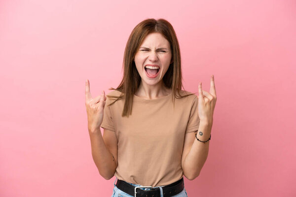 Young English woman isolated on pink background making horn gesture