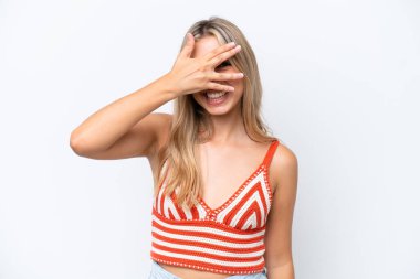 Beyaz arka planda soyutlanmış beyaz tenli genç bir kadın elleriyle gözlerini kapatıyor ve gülümsüyor.