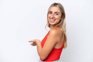 Beyaz arka planda soyutlanmış beyaz tenli genç bir kadın davet edilmek için ellerini yana uzatıyor.