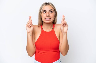 Beyaz arka planda izole edilmiş beyaz tenli genç bir kadın parmaklarını çapraz yapıp en iyisini diliyor.