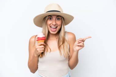 Beyaz arka planda izole edilmiş kornet dondurmalı beyaz bir kadın şaşırmış ve parmağıyla kenarı işaret ediyor.