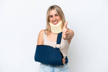 Kırık kollu ve askı takan bir kadın beyaz arka planda izole edilmiş iyi bir anlaşma için el sıkışıyor.