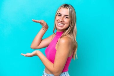 Mavi arka planda izole edilmiş beyaz bir kadın ilan vermek için kopyalama alanı tutuyor.