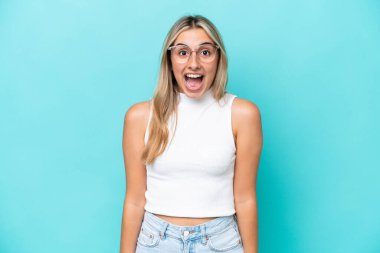 Mavi arka planda yalıtılmış beyaz bir kadın. Şaşırtıcı bir yüz ifadesi var.