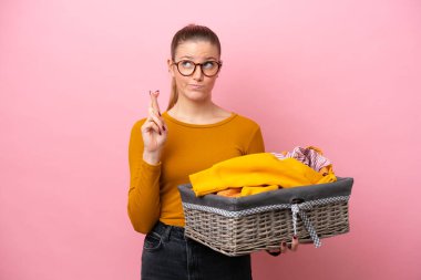 Pembe arka planda izole edilmiş çamaşır sepetini tutan beyaz bir kadın dua ederek en iyisini diliyor.