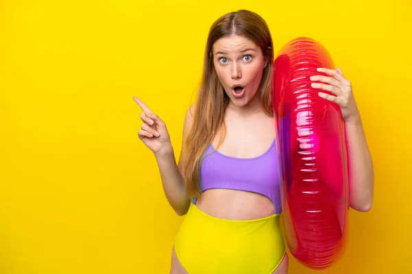 Jovem Caucasiana Segurando Colchão Isolado Fundo Amarelo Surpreendido Apontando Lado — Fotografia de Stock