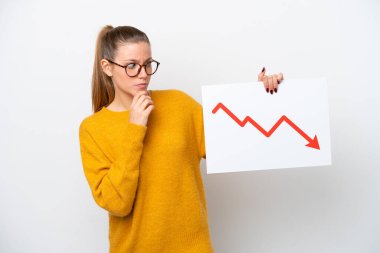 Beyaz arka planda izole edilmiş genç beyaz bir kadın elinde azalan bir istatistik oku sembolü ve düşüncesi olan bir tabela tutuyor.
