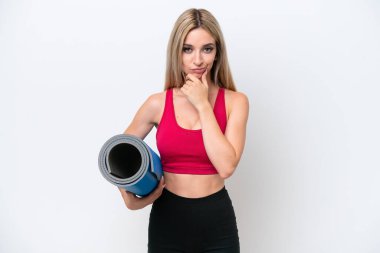 Genç sarışın kadın yoga derslerine giderken beyaz arka planda izole edilmiş bir minder tutuyor.