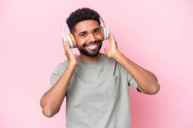 Pembe arka planda izole edilmiş genç Brezilyalı adam müzik dinliyor.
