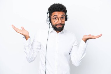 Telemarketer Brazilian man working with a headset isolated on white background having doubts while raising hands